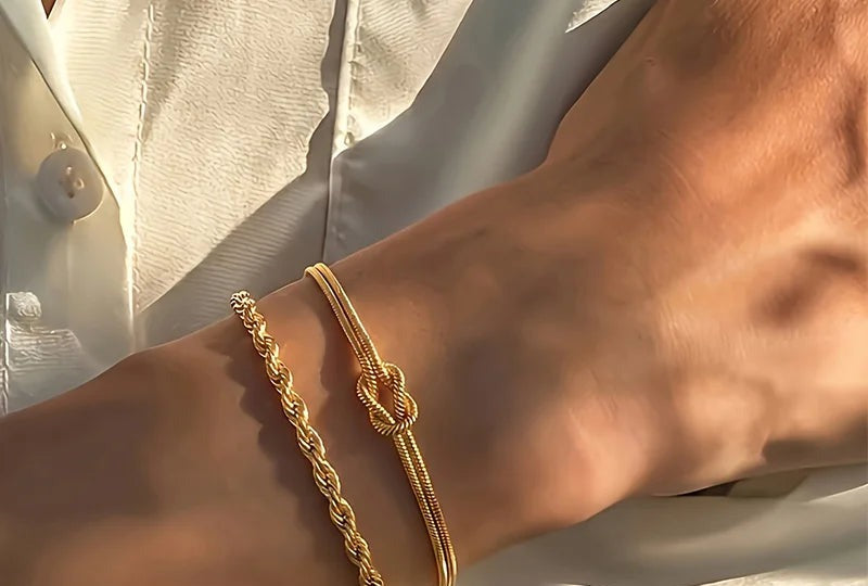 Wrist wearing a gold rope chain and a knotted snake chain bracelet