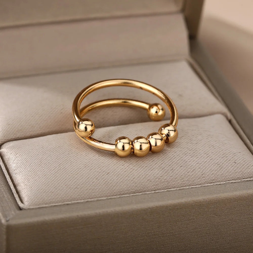 Gold adjustable spinner ring with spinning beads on a cream surface
