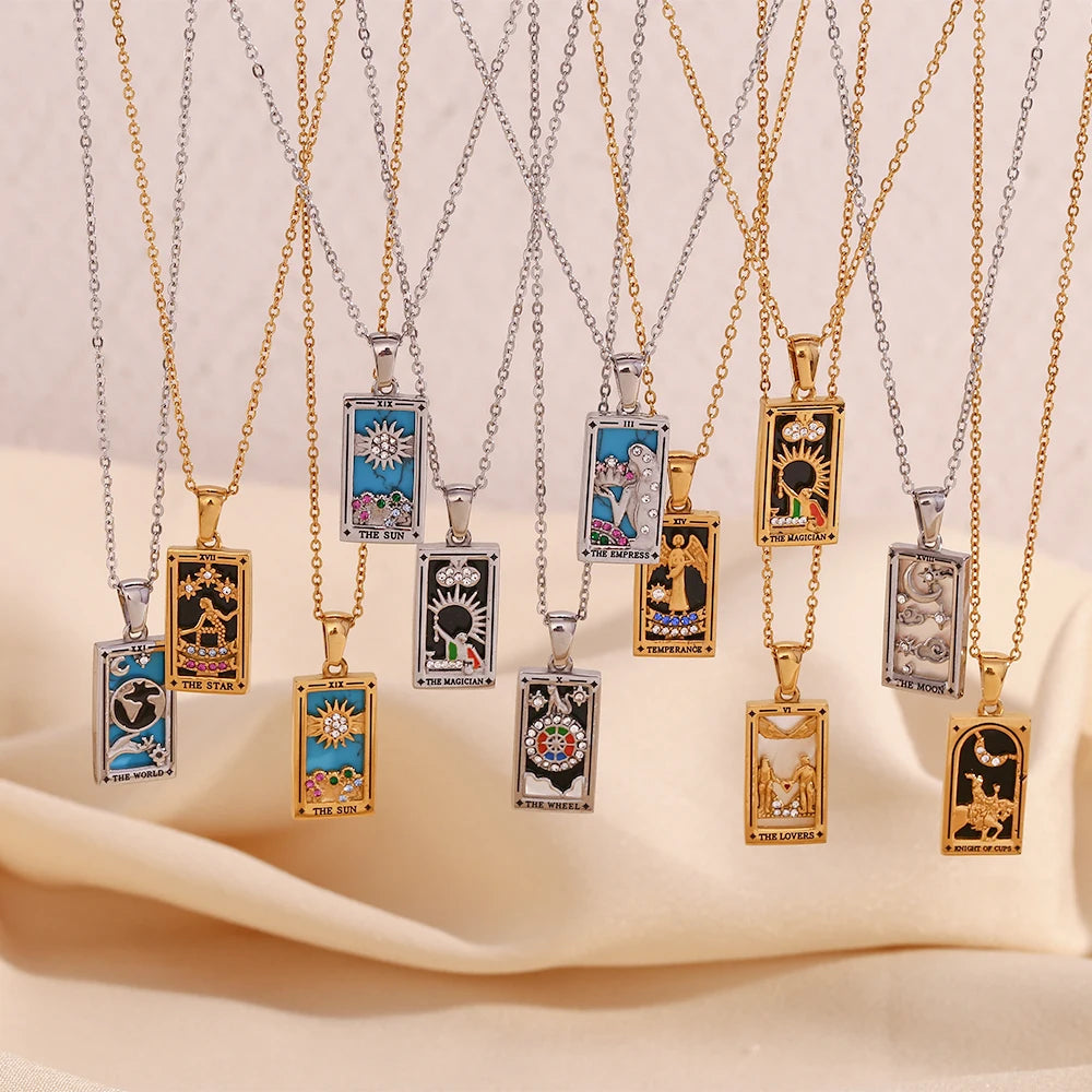Gold-tone and silver-tone tarot card pendant necklaces hanging in a row above cream fabric