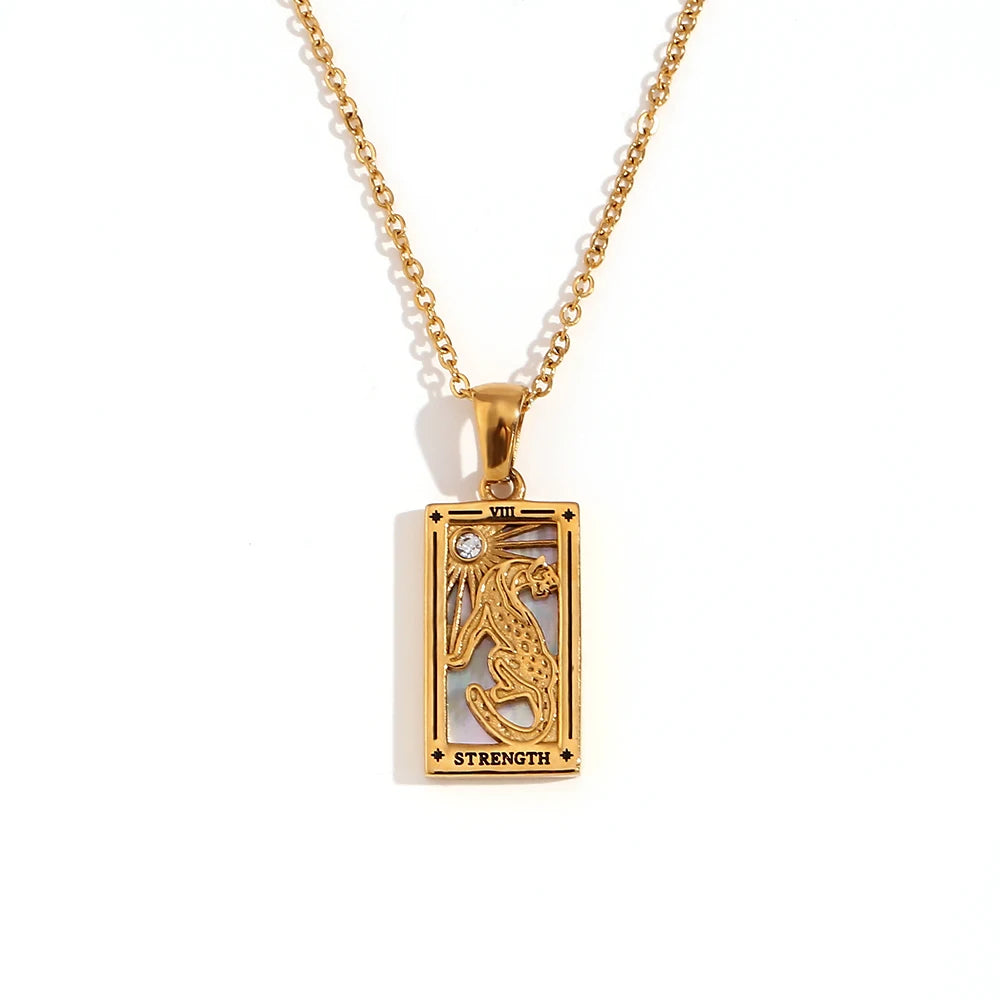 Gold-tone Strength tarot card pendant necklace with cut-out lion design and a small clear stone, on white