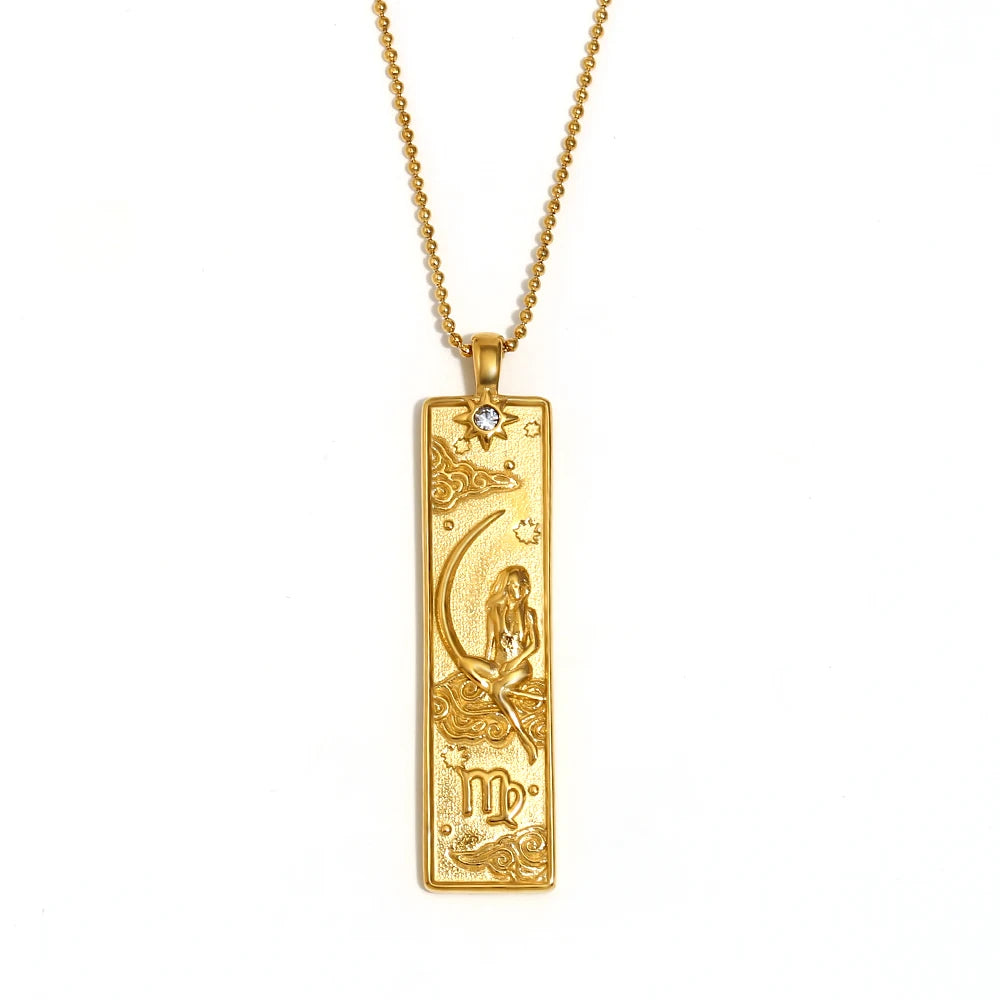 Gold-tone Virgo zodiac bar pendant necklace with engraved maiden and moon, and a small clear stone, on white