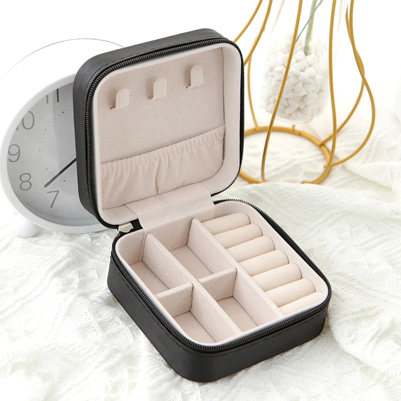 Black zip-around travel jewellery case, open, showing ring rolls and compartments