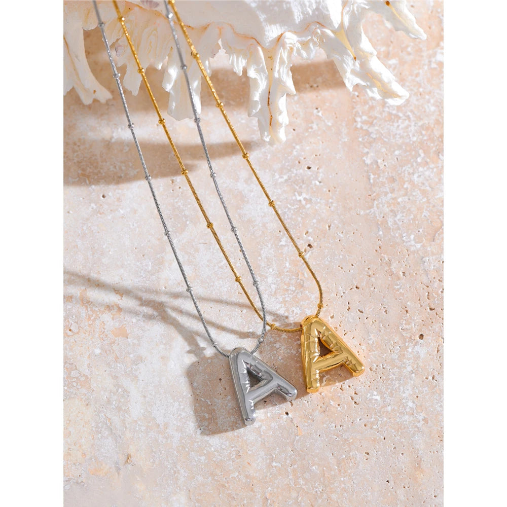 Gold letter pendant necklace on a fine chain, shown on a display