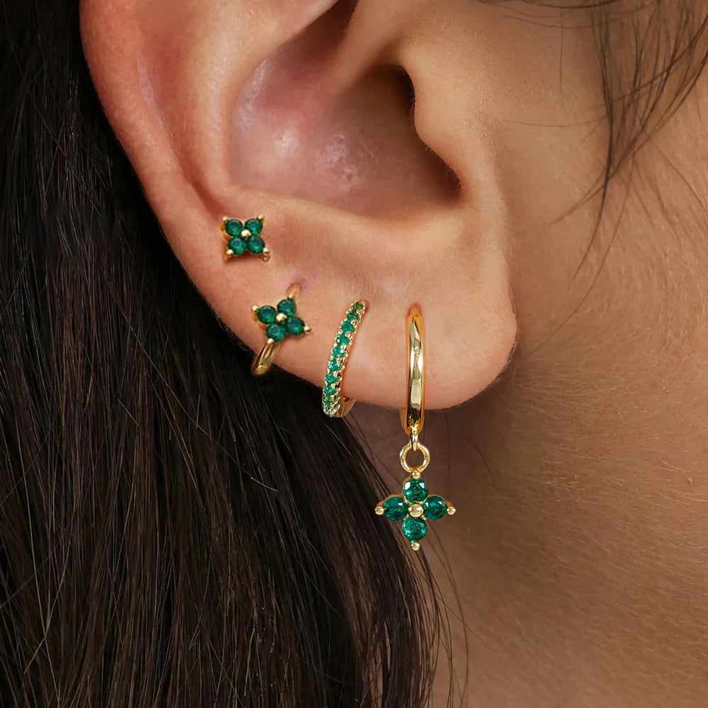 Gold ear stack with a flower stud, huggies and a charm hoop worn on the ear