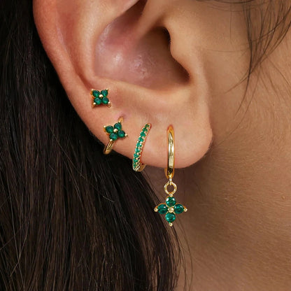 Gold ear stack with a flower stud, huggies and a charm hoop worn on the ear