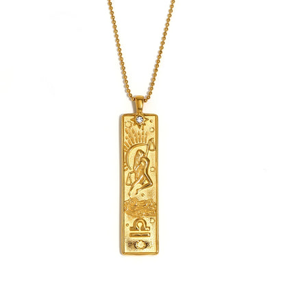 Gold-tone Libra zodiac bar pendant necklace with engraved figure and scales symbol, and a small clear stone, on white
