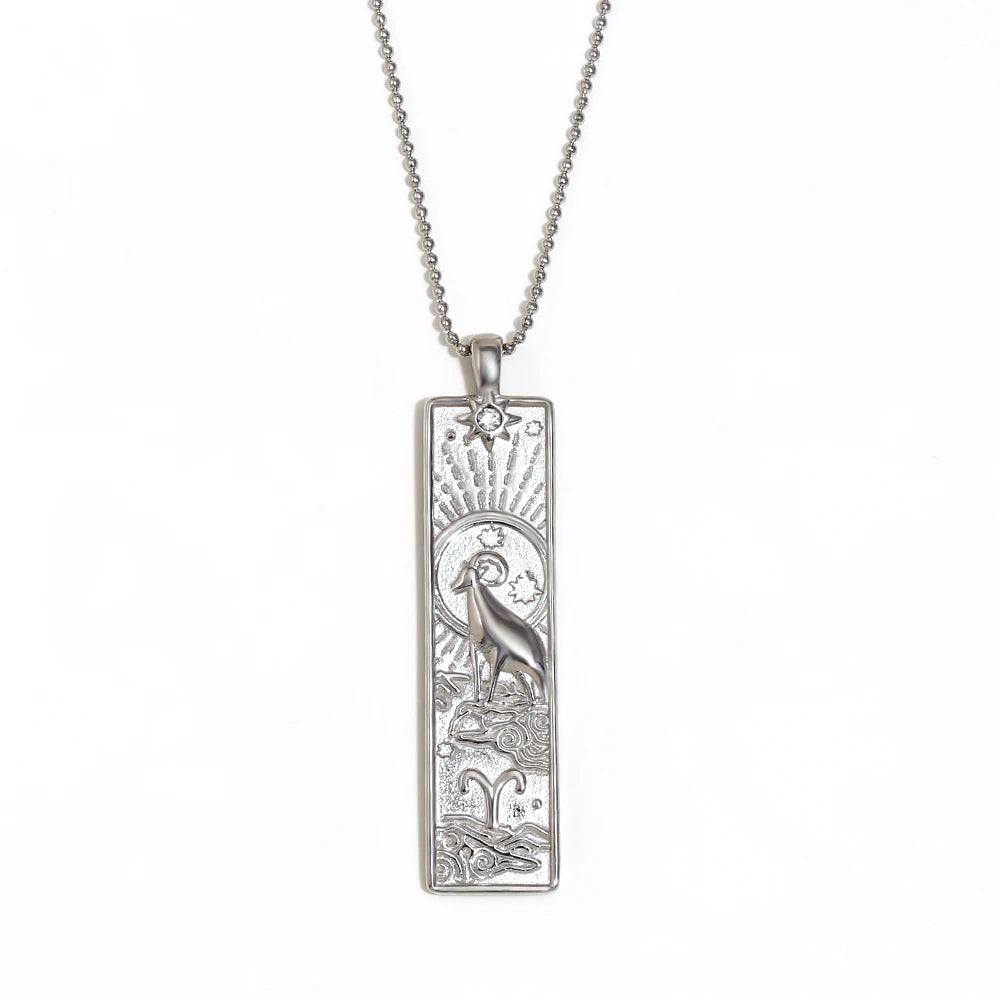 Silver-tone Aries zodiac bar pendant necklace with engraved ram and a small clear stone, on white