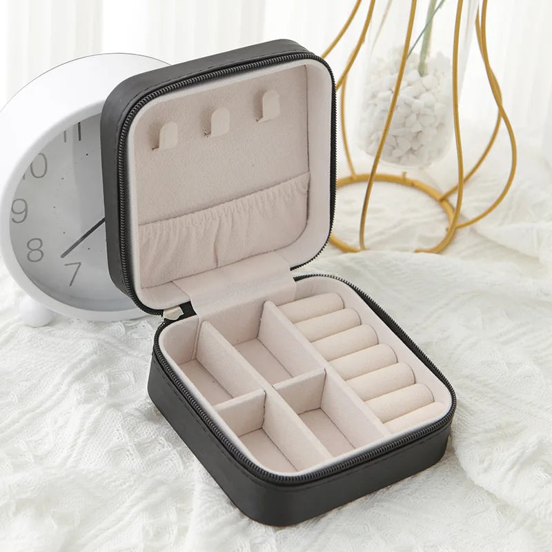 Black travel jewellery case, open, with a soft blush lining, ring rolls and earring slots