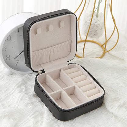 Black travel jewellery case, open, with a soft blush lining, ring rolls and earring slots