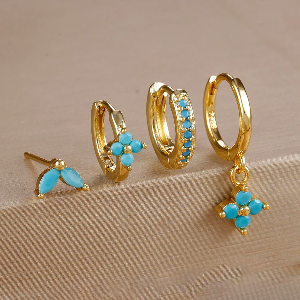 Gold-tone four-piece ear stack with turquoise stones: leaf stud, flower huggie, pavé huggie and flower drop hoop