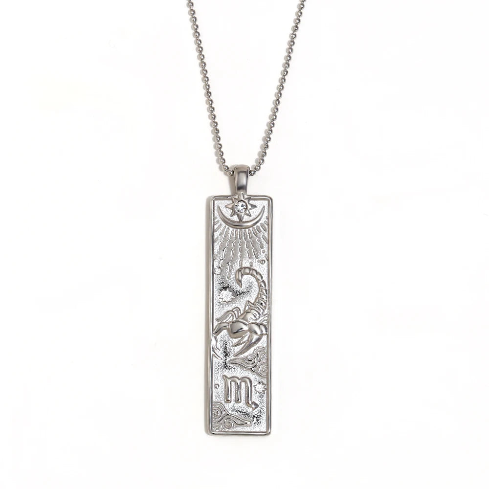 Silver-tone Scorpio zodiac bar pendant necklace with engraved scorpion and a small clear stone, on white