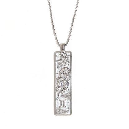 Silver-tone Gemini zodiac bar pendant necklace with engraved twins and a small clear stone, on white
