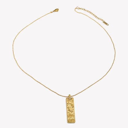 Gold zodiac bar pendant on a fine ball chain laid flat
