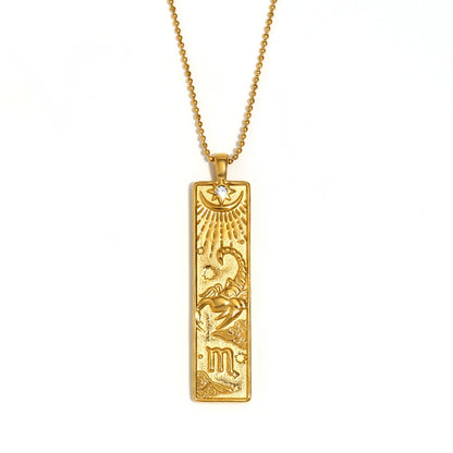 Gold-tone Scorpio zodiac bar pendant necklace with engraved scorpion and a small clear stone, on white